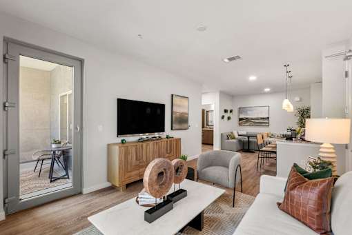 A modern living room with a white sofa, a wooden cabinet, and a flat-screen TV.