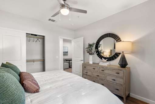 A bedroom with a bed, dresser, mirror, and a ceiling fan.