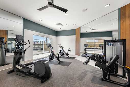 A gym with a variety of exercise equipment including treadmills, stationary bikes, and weight machines.