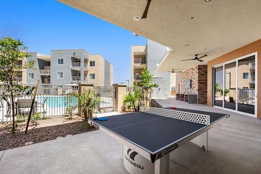 A table tennis table is in the middle of a patio.