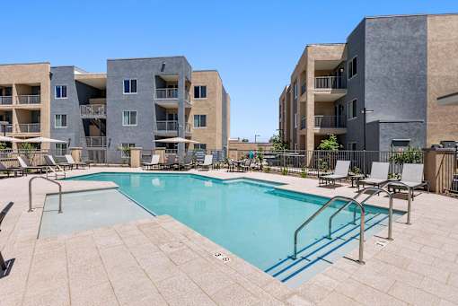 A swimming pool surrounded by lounge chairs and buildings.