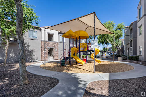 A playground with a yellow slide and a canopy.