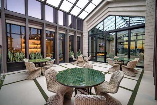 A glass-roofed room with a green table and chairs.