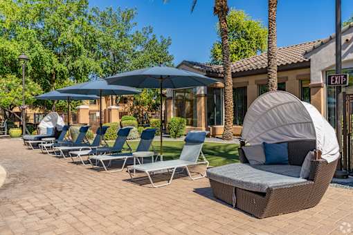 A row of lounge chairs are arranged on a patio.