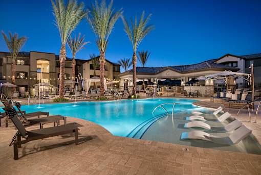 A pool surrounded by palm trees and lounge chairs.