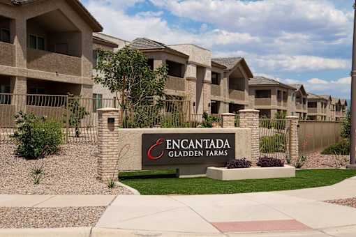 A sign that says Encantada Gladen Farms in front of some houses.