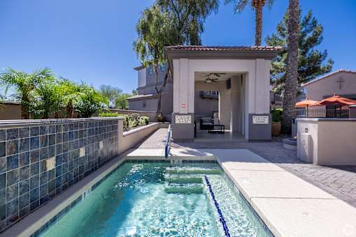 A pool with a blue tiled wall and a white building in the background.