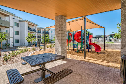 A playground with a red slide and a picnic table.