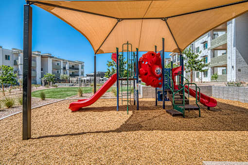 A playground with a red slide and a yellow canopy.