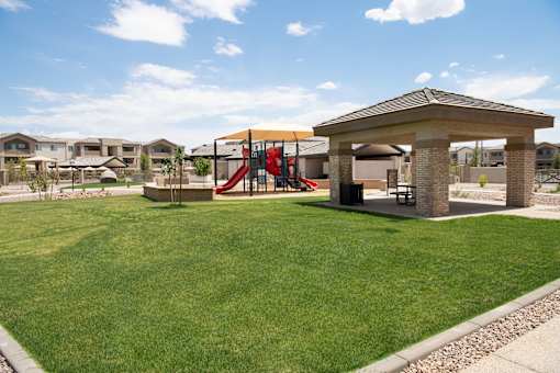 A playground with a red slide and a brown pavilion.