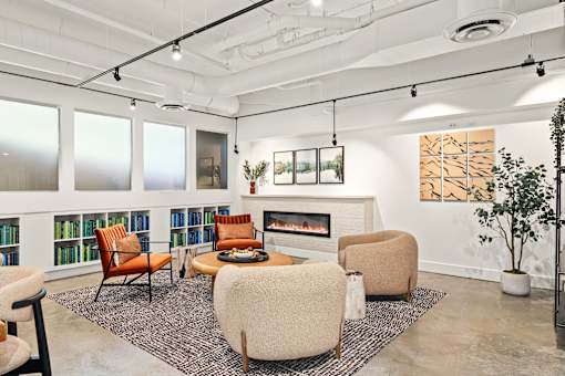 A living room with a fireplace, chairs, and a rug.