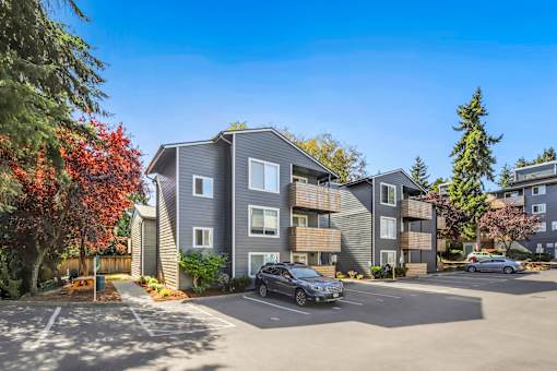 A modern apartment complex with a parking lot in front.