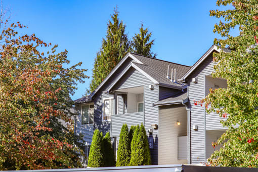 a gray house with trees and a blue sky