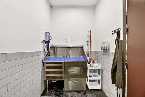 A clean, white-tiled kitchen with a stainless steel sink and a blue mat on the counter.