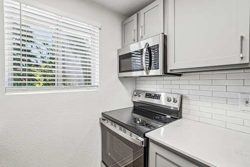 A kitchen with a stove, microwave, and oven.