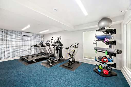 A home gym with a treadmill, exercise bike, and other equipment.