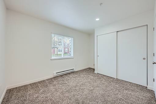 A room with a window, carpet, and a door.