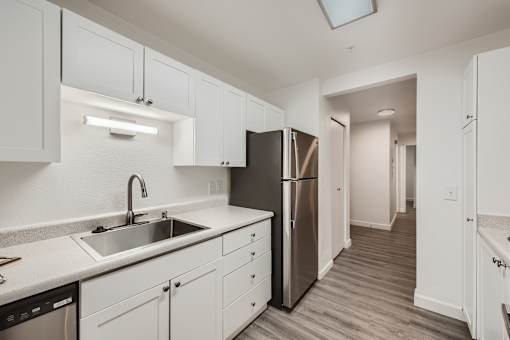A kitchen with white cabinets and a stainless steel refrigerator.
