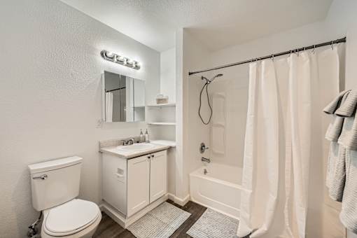 A white bathroom with a toilet, sink, and shower.