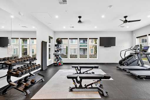 A spacious gym with a variety of equipment including treadmills, stationary bikes, and dumbbells.
