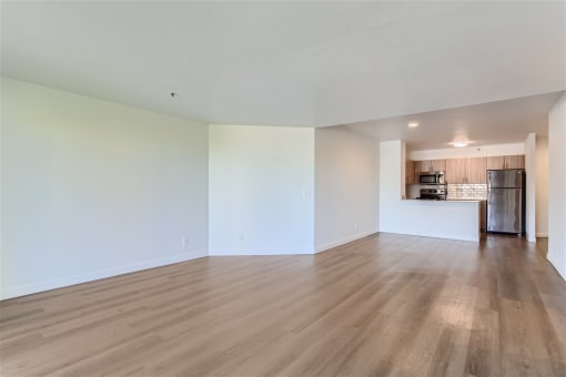the living room and kitchen of an empty apartment with wood flooring
