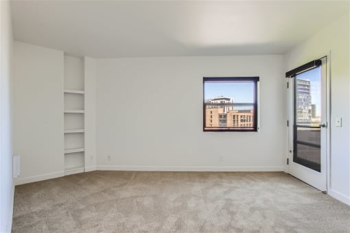 an empty living room with a window and a door to a balcony