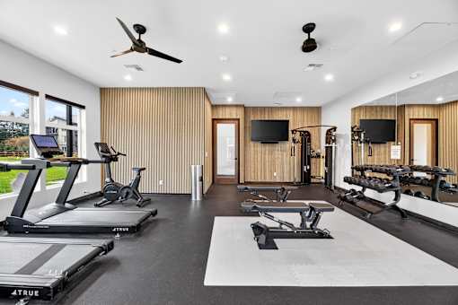 A spacious home gym with treadmills, exercise bikes, and a television.