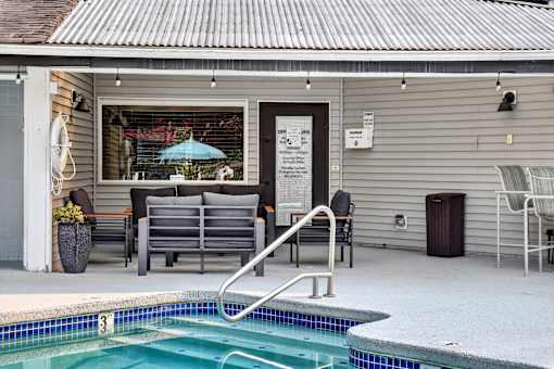 A pool in a backyard with a chair and a table.
