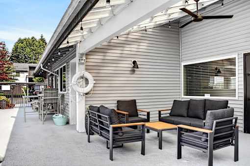 A patio with a table and chairs is covered by a roof.
