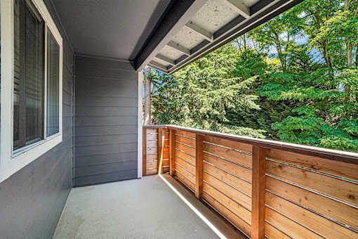 A balcony with a grey wall and a wooden railing.