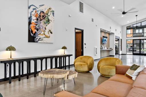 A living room with a large painting on the wall and a long brown leather couch.