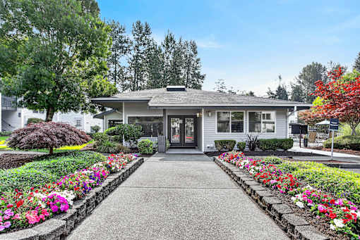 A house with a grey roof and a grey front door with a concrete walkway leading to it.