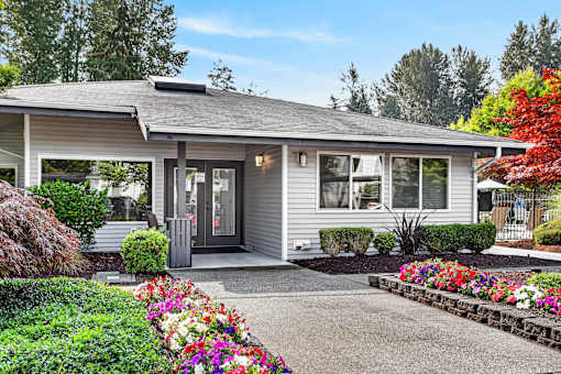 A house with a grey roof and a grey door surrounded by a garden with flowers.