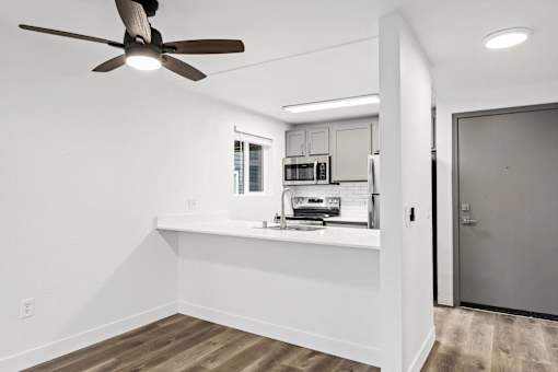 A modern kitchen with a fan and wooden floors.