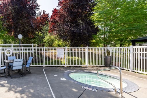 a hot tub with a table and chairs next to a fence