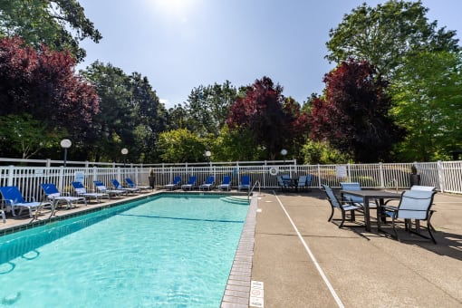 a swimming pool with chairs and a table next to it