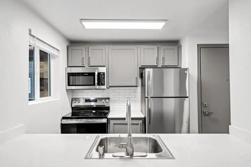 A kitchen with a stove, microwave, refrigerator, and sink.