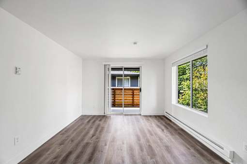 A room with a white wall and a window with a view of trees.