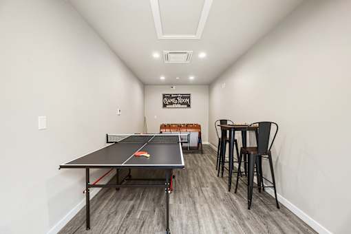 A ping pong table is in the middle of a room with a bar area.