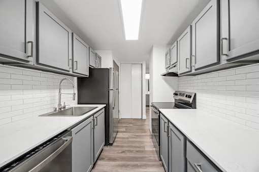 A modern kitchen with white cabinets and a black refrigerator.