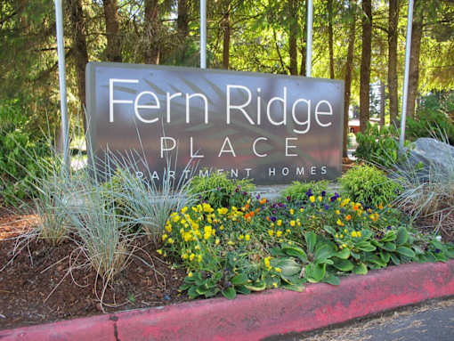 A sign that says Fern Ridge Place in front of some trees.