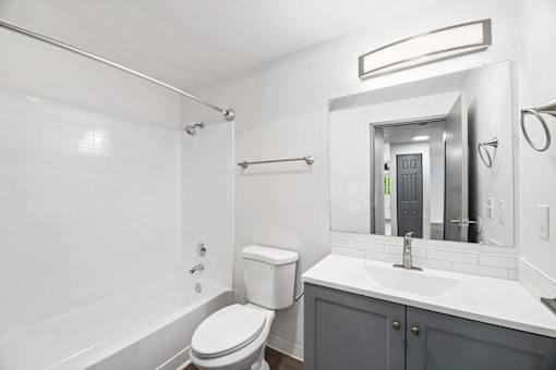 A white bathroom with a toilet, sink, and bathtub.