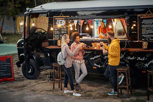 Three people are standing in front of a food truck.
