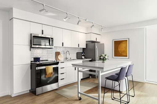 A modern kitchen with a white color scheme and stainless steel appliances.