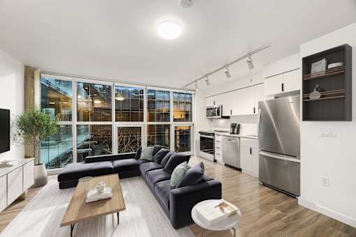 A modern kitchen with a large window and a black couch.