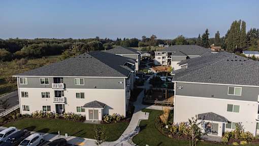 A large apartment complex with multiple buildings and a parking lot in front.