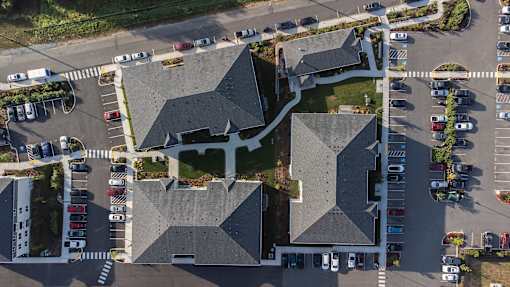 A parking lot with cars and a building with a grey roof.