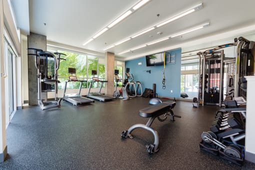 a large fitness room with cardio equipment and a flat screen tv