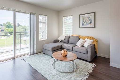 a living room with a gray couch and a glass coffee table