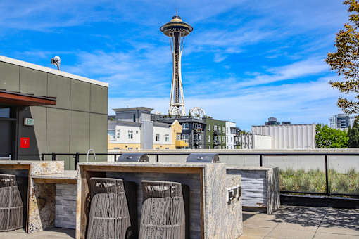 A view of a rooftop with a table and chairs and a building in the background.